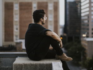 Man sitting on ledge in city