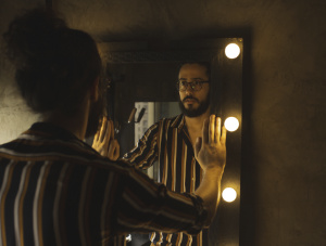 Man touching mirror looking at himself